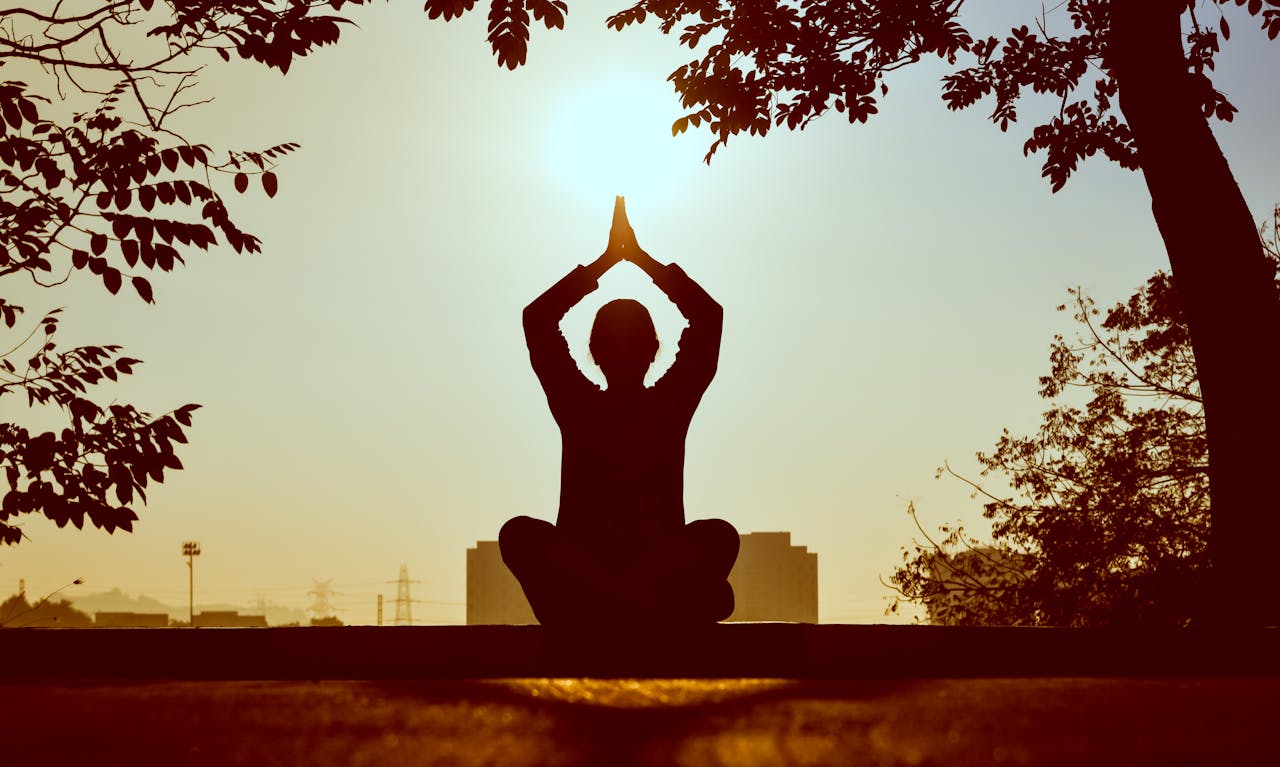 home-hero Silhouette of a person practicing yoga outdoors during sunrise, creating a calming atmosphere.