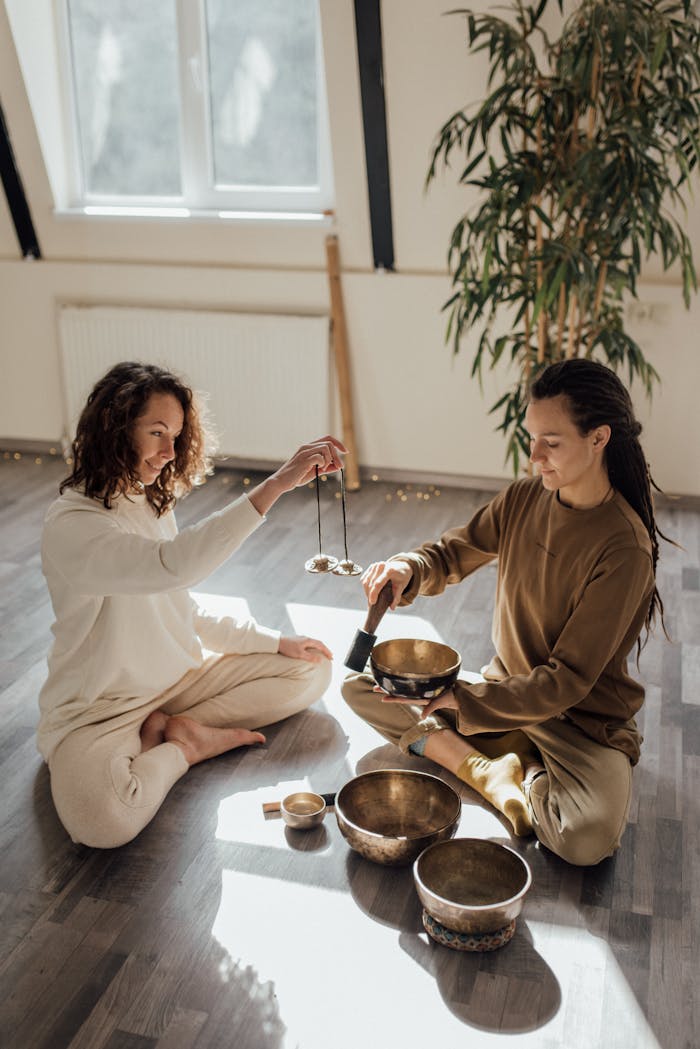 services-05 Two adults meditating indoors with Tibetan singing bowls, embracing tranquility and wellness.